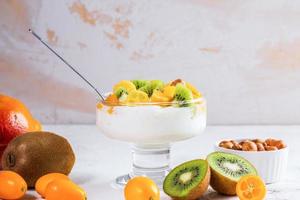 tigela de vidro na haste com iogurte e frutas frescas em fundo branco. foto