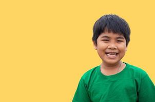 o menino vestia uma camisa verde e sorria. em um fundo amarelo foto