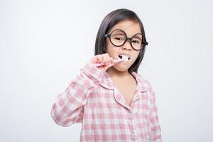 menina ásia escovando os dentes alegremente fundo branco foto