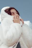 garota com um casaco de pele branco sob um céu com nuvens foto