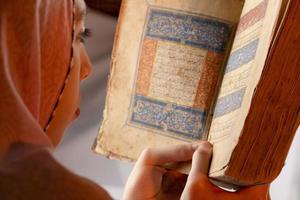 uma jovem lendo o Alcorão sagrado de um moshaf raro foto
