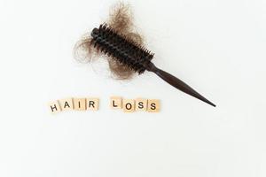 perda de cabelo no pente, problema sério diário de perda de cabelo, em fundo branco. inscrição em letras de madeira.