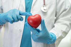 médico segurando um coração vermelho na enfermaria do hospital, conceito médico forte e saudável. foto