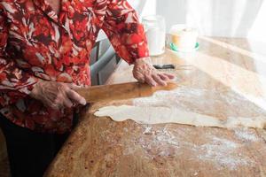 mãos irreconhecíveis de mulher com um rolo preparando casadielles recheados com nozes. gastronomia tradicional foto