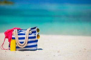 bolsa listrada azul com acessórios de praia em uma praia
