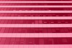 vista em perspectiva de baixo na fachada do prédio de escritórios, arranha-céu moderno tonificado em viva cor magenta. inspirado na cor pantone do ano de 2023. foto horizontal com lugar para texto.