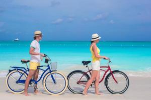 casal caminhando com bicicletas na praia foto