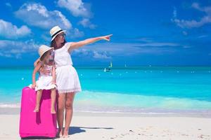 mãe e filha com bagagem em uma praia tropical foto