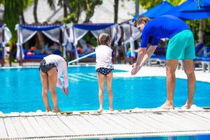 maldivas, sul da ásia, 2020 - pai ensinando suas filhas a mergulhar em uma piscina foto