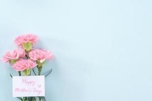 linda e elegante flor de cravo rosa sobre fundo de mesa azul claro brilhante, conceito de presente de flor para o dia das mães, vista superior, configuração plana, sobrecarga foto