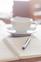 caderno com uma caneta e um café foto