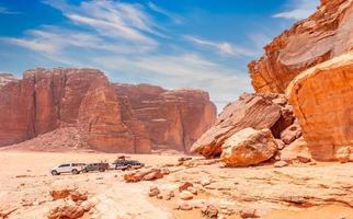 pedras vermelhas e rochas do deserto de wadi rum com carros ao fundo, jordânia foto
