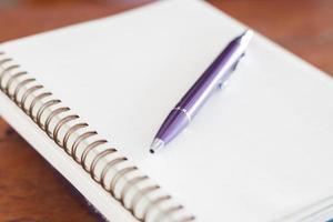 caneta roxa e um caderno espiral foto