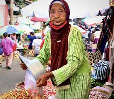 badung, bali - 13 de janeiro de 2023 foto de um velho vendedor que ainda vende pimentões em um mercado tradicional de Bali