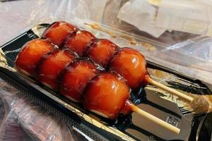 dango é um bolinho japonês feito de farinha de arroz misturada com farinha de arroz uruchi e farinha de arroz glutinoso. dango com molho doce no mochi japonês foto