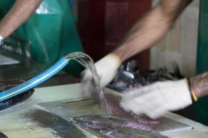 maldivas masculinas limpando as mãos de peixe no mercado foto