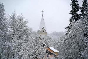 floresta enquanto nevava no inverno com cúpula de igreja foto