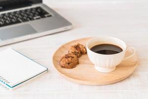 café preto e biscoitos com laptop e caderno foto
