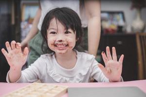 garota feliz e fofa com um chocolate no rosto foto