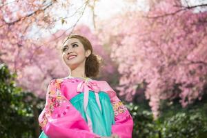 hanbok, o vestido tradicional coreano e linda garota asiática com sakura foto