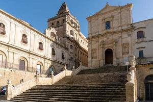 noto, itália-8 de maio de 2022-pessoas passeiam em noto em frente à igreja de san francesco d'assisi all'immacolata durante um dia ensolarado foto