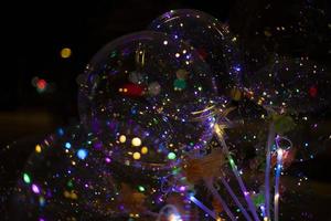 bolas coloridas com lâmpadas dentro em fundo escuro. textura de luzes no escuro. detalhes do feriado. Decoração de Natal. foto