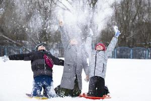 crianças no inverno. três amiguinhos estão brincando na neve. foto