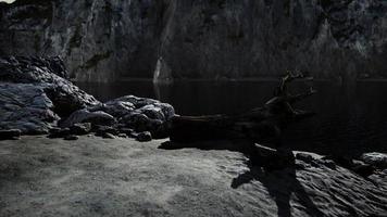 praia de areia preta escondida entre rochas vulcânicas borradas foto