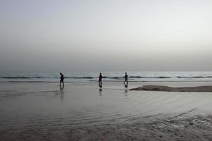 praia solitária com pessoas passeando na areia na beira das ondas do mar foto
