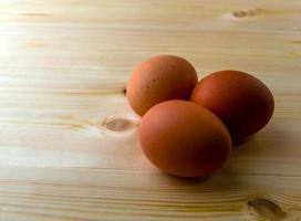 três ovos em uma mesa de madeira. foto