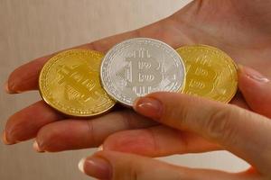 mão segura três moedas de moeda digital bitcoin foto
