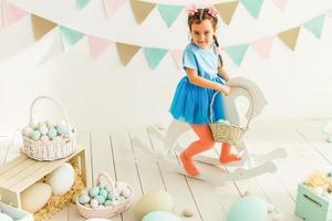 menina bonitinha com orelhas de coelho e cesta de ovos de páscoa foto