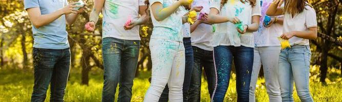 alegres jovens amigos multiétnicos com tinta colorida em roupas e corpos se divertindo juntos no festival de holi foto