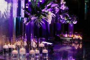 velas acesas em frascos de vidro ficam no chão do salão de celebração. fundo. copie o espaço. foto