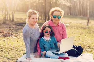 família com um laptop em um parque foto