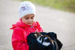 menina bonitinha com seu gatinho de estimação num dia quente de verão. crianças e animais. foto