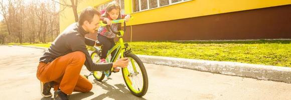 closeup de um pai recortado consertando o pneu de bicicleta da filha foto