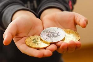 bitcoin nas mãos de uma criança o menino segura uma moeda metálica de moeda criptográfica em suas mãos foto