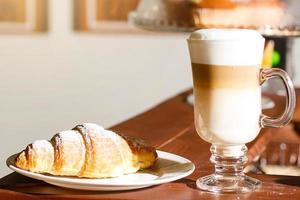 café com leite e croissant em uma mesa de madeira foto