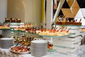 mesa de banquete de catering lindamente decorada com saladas de profiteroles de hambúrgueres e lanches frios foto