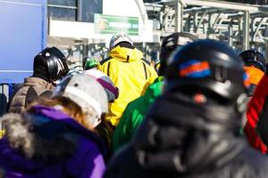 pessoas no teleférico, linha de esquiadores e snowboarders foto