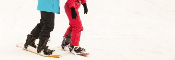 par de snowboarders no topo de uma pista de esqui no resort de inverno downhill em um dia ensolarado. foto