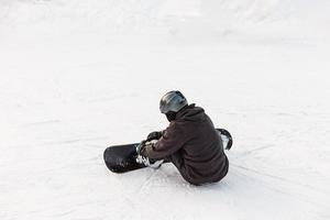 snowboarder sentado. conceito de esporte de inverno com cara de aventura no topo da montanha pronto para descer foto