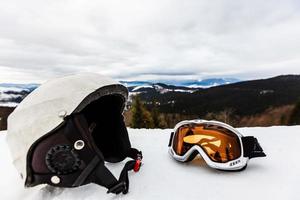 capacete de esqui e óculos de esqui estão na neve foto