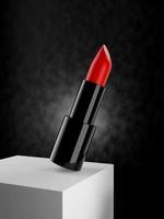 close-up de um batom vermelho no bloco branco com fundo texturizado escuro - ilustração 3d render foto