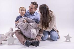 família no estúdio se divertindo isolado no fundo branco. pai, mãe e dois filhos se abraçam e sorriem foto