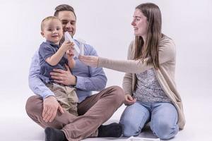 família no estúdio se divertindo isolado no fundo branco. pai, mãe e dois filhos se abraçam e sorriem foto