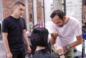 foto de um cabeleireiro aparando as pontas molhadas do cabelo da cliente usando um pente e uma tesoura