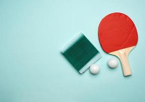 duas raquetes de madeira e uma bola de plástico laranja para jogar tênis de mesa foto