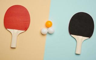 duas raquetes de madeira e bolas de plástico para jogar tênis de mesa foto
